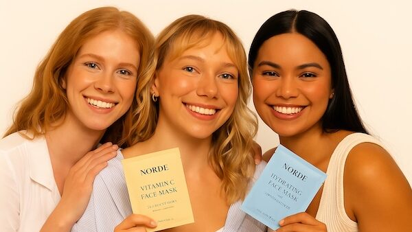 Kolme iloista henkilöä pitelee ihonhoitotuotteita, NORDE-brändin yhteisöllinen kuva.